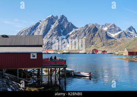 Stampde Cafe in roten Holzhaus auf Stelzen mit Blick auf Meer und Berge im Fischerdorf Sund, Insel Flakstadøya, Lofoten, Norwegen Stockfoto