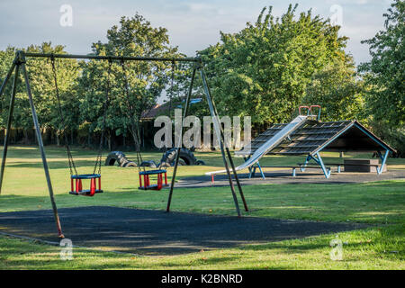 Kinderspielplatz/Spielplatz mit Schaukeln und Rutsche, und niemand herum, in der Ortschaft Langtoft, Lincolnshire, England, UK. Stockfoto