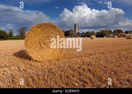 Strohballen und Bereich der Stoppeln, mit St. James Kirche, Southrepps, Norfolk, UK August 2014. Stockfoto