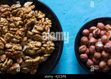 Ein Teil der Runde Holzplatten mit den geräumten Walnüsse und Haselnüsse auf einem blauen Hintergrund. Stockfoto