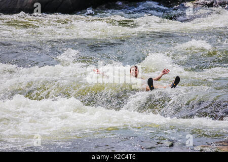 Junge Erwachsene Abkühlung im James River Rapids, Richmond, Virginia - August 2017. Stockfoto