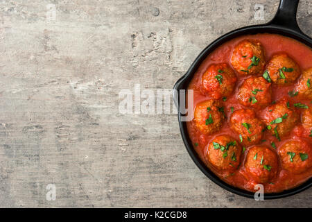 Hackfleischbällchen mit Tomatensauce in Eisenpfanne auf Holztisch. Ansicht von oben Stockfoto