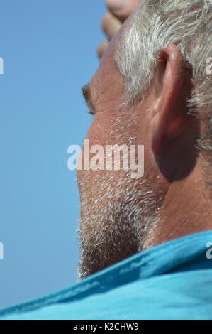 Weiß Grau graue Haare unrasiert Bart Schatten am hinteren Profil Mitte Alter bräunen gebräunte Mann unter strahlend blauem Himmel Stockfoto