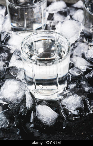 Alkohol und Cocktails. Drei Gläser Wodka auf einer Schiefertafel Fach, mit Eis. Auf einem schwarzen Steintisch. Stockfoto