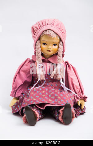 Porträt einer Sitzung Keramik Porzellan handmade Vintage Doll mit gelben Gesicht und zwei Pigtails in einem alten Textil Gestrickte rosa Kleid mit Aufdruck in Groß Stockfoto