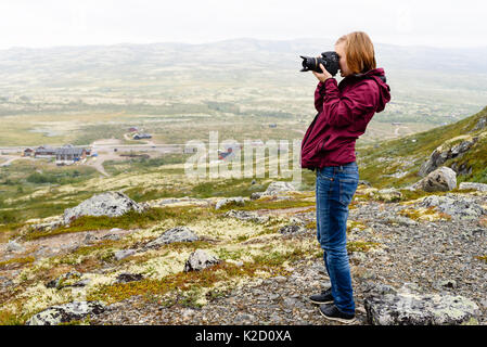 Junge Erwachsene kaukasische Frau Fotografieren von bergigen Landschaft an einem nebligen Sommertag. Stockfoto