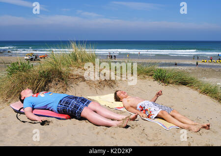 Zwei Jungen im Teenageralter Sonnenbaden in den Sanddünen auf porthtowan Beach, Cornwall, England, Großbritannien. Stockfoto