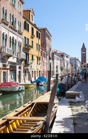 Blick entlang des Rio de San Barnaba, Cannaregio, Venice, Italien in Richtung der Glockenturm der Chiesa San Barnaba mit einem alten bunten gelb Holz- Boot in den fo Stockfoto