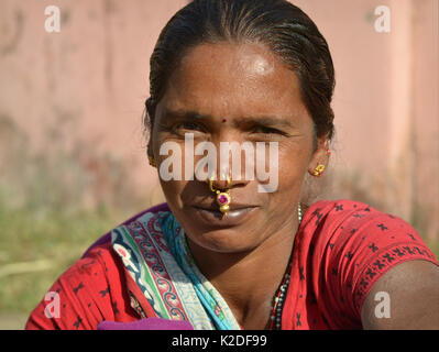 Junge indianische Adivasi-Frau (Stamm der Desia Kondh alias Stamm der Kuvi Kondh) mit Gold-und-gemsteinernem Stammesnasenschmuck lächelt für die Kamera. Stockfoto