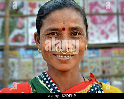 Indische Adivasi-Frau (Dongria-Kondh-Stamm) mit drei goldenen Nasenringen, Stammesohrringen und rotem Bindi auf der Stirn lächelt für die Kamera. Stockfoto