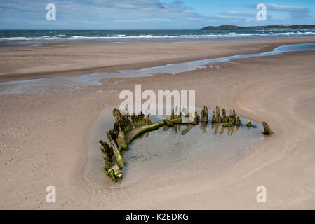 Wrack der Brig Athena ausgesetzt bei Ebbe auf aberffraw Beach, Anglesey, Nordwales, mit llanddwyn Island und Snowdonia im Hintergrund, UK August 2016. Stockfoto