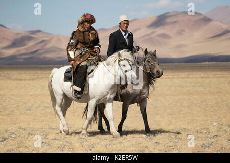 Eagle Hunter (links) und muslimischen Reiter zu Fuß auf ihren Mongolischen Pferden, im Eagle Jäger Festival, in der Nähe von Sagsai, Bayan-Ulgii Aymag und Mongolei. September 2014 .. Stockfoto