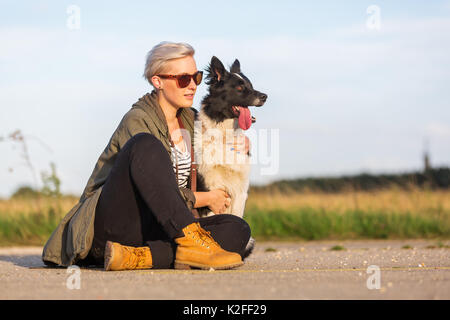 Porträt einer Frau sitzt auf einer Straße mit einem Border Collie Stockfoto