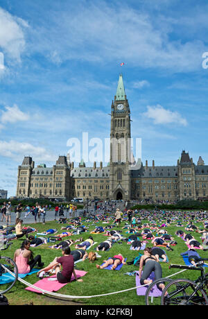 Freie Gruppe yoga Class auf dem Parliament Hill in Ottawa, Kanada. Yoga vor dem Parlament. Stockfoto