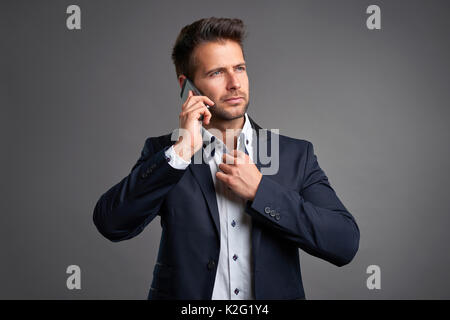 Ein zuversichtlich elegante hübscher junger Mann auf einem Smartphone sprechen Stockfoto