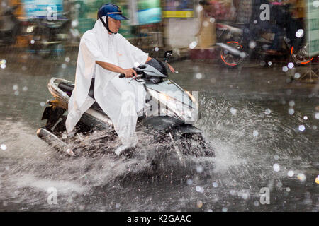 Mann auf dem Motorrad fährt durch Hochwasser und Starkregen auf Bui Vien Street, Ho Chi Minh City (Saigon), Vietnam Stockfoto
