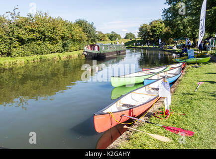 Bunte Kanus günstig auf dem Grand Union Canal an Marsworth, mit einem schmalen Boot im Hintergrund, in der Nähe von Aylesbury, Bucks Stockfoto