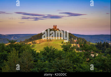 Obere Kirche mit zwei Türmen und barocken Kalvarienberg in Banska Stiavnica, Slovaka bei Sonnenuntergang. Banska Stiavnica ist eine vollständig erhaltene mittelalterliche Stadt und Stockfoto