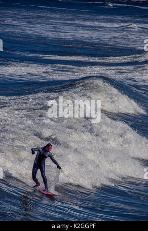 Surfer auf Surfbrett reiten eine Welle in saltburn, North yorkshire, großbritannien Stockfoto