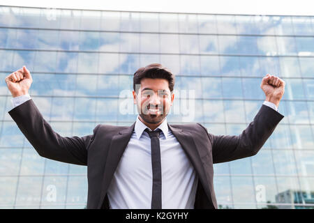 Erfolgreiche glücklich lächelnde Arabisch östlichen indischen Geschäftsmann oder Arbeitnehmer im schwarzen Anzug mit Krawatte und Hemd mit Bart stand vor einem Büro buildi Stockfoto