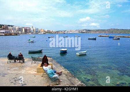 Paare auf Bänken in den Blick über St. Paul's Bay, Bugibba, Malta, Europa suchen. Stockfoto