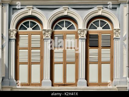 Traditionelle shop Haus außen mit braunen und weißen Holz Lamellenfensterläden, Bogenfenster und verzierten Säulen im Chinatown von Singapur Stockfoto