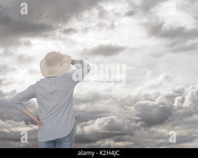 Frau auf der Suche nach Wolken. Regentag auf dem Weg. Zukunftssicherheit Konzept. Stockfoto