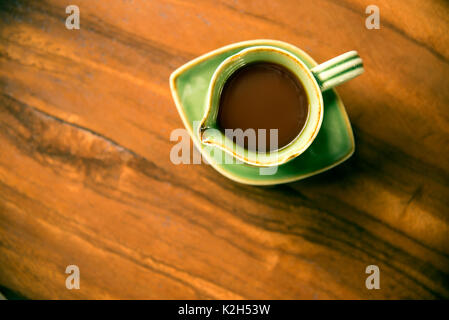 Eine Tasse Kopi Luwak Kaffee top Blick auf einen hölzernen Tisch in eine grüne Schale. Stockfoto