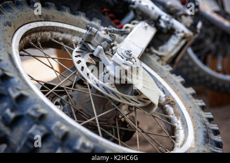 Detailansicht der hinteren Rad und Radnabe einer schmutzigen, grunge Motocross Motorrad, das auf den Boden legt. Stockfoto