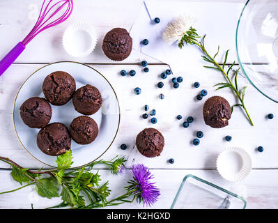 Blick von oben auf eine weiße Holztisch mit Muffins und verschiedene Dekorationen auf. Stockfoto