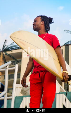 Junge afrikanische amerikanische Mann mit einem Surfbrett draußen Stockfoto