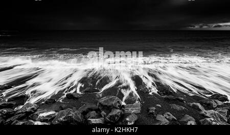 Dramatische Ozean Wellen, die auf der felsigen Strand, Schwarz und Weiß Stockfoto