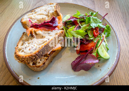 Staal Räucherlachs Sandwich mit Rote-bete-creme Käse auf Sauerteigbrot mit Salat garnieren Stockfoto