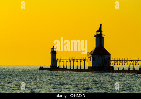 Der Leuchtturm und Pier in St. Joseph, Michigan, USA, mit einem gelben Himmel bei Sonnenuntergang hervorgehoben Stockfoto