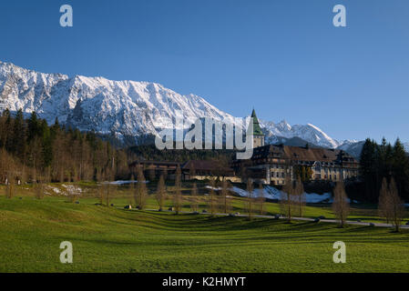 Hotel Schloss Elmau vor der schneebedeckten Berge und warmen Abendsonne, Bayern, Deutschland Stockfoto