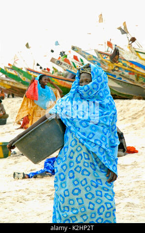 Eine Frau wartet auf die Fischerboote auf den Strand in Nouakchott, Mauretanien Stockfoto