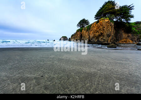 Klippe am Ende der entfernten Strand hat Haus und einzigen Baum auf der Oberseite Stockfoto