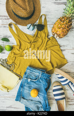 Farbenfrohe Sommer Mode outfit Flachbild-legen. Denim Shorts, Stroh Sonnenhut, Gelb oben, espadrillas, Gelb Leder Tasche, Sonnenbrille, Ananas-, Limonen-, Limetten- und Le Stockfoto