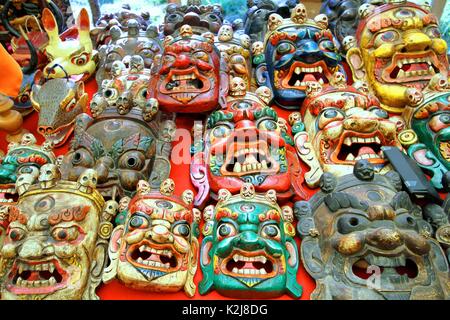 Bunt bemalte traditionelle Holzschnitzerei Maske Verkauf auf dem Markt, Bhutan. Stockfoto