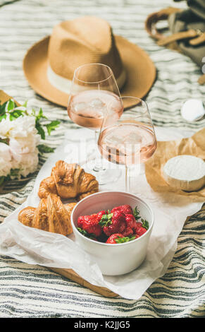 Im französischen Stil romantisch Sommer Picknick Einstellung. Flachbild-lay Gläser rose Wein mit Eis und Erdbeeren, die in der Schüssel, Croissants, Brie Käse, Strohhut, peon Stockfoto