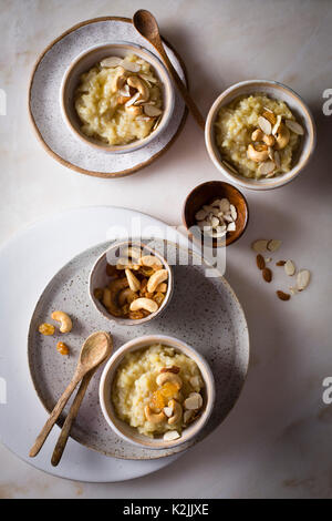 Süße pongal/Reis linsen Pudding garniert mit gerösteten Nüssen in einzelnen servieren Schalen auf einem Marmortisch in der Ansicht von oben Stockfoto