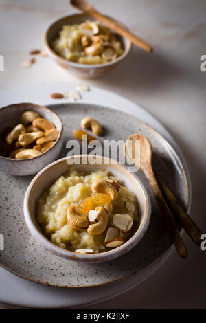 Süße pongal/Reis linsen Pudding garniert mit gerösteten Nüssen in einzelnen servieren Schalen auf einem Marmortisch in der Ansicht von oben Stockfoto