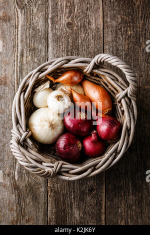 Verschiedene Arten von Zwiebeln im Korb auf Holz- Hintergrund Stockfoto