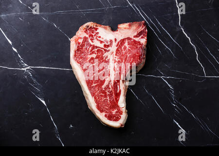 Rohes Fleisch trocken Steak T-Bone auf dunklem Marmor Hintergrund Stockfoto