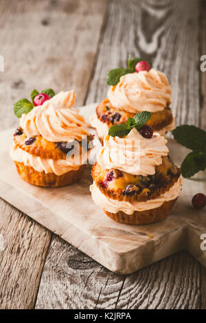 Cranberry pumpkin Cupcakes mit Cream Cheese frosting auf rustikalen Urlaub Tabelle Stockfoto