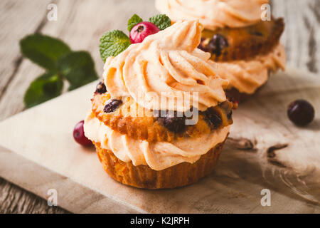 Cranberry pumpkin Cupcakes mit Cream Cheese frosting auf rustikalen Urlaub Tabelle Stockfoto