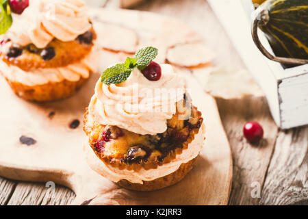 Cranberry pumpkin Cupcakes mit Cream Cheese frosting auf rustikalen Urlaub Tabelle Stockfoto