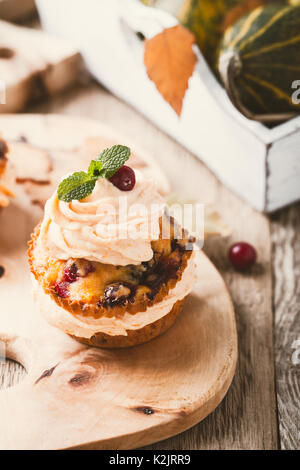 Cranberry pumpkin Cupcakes mit Cream Cheese frosting auf rustikalen Urlaub Tabelle Stockfoto