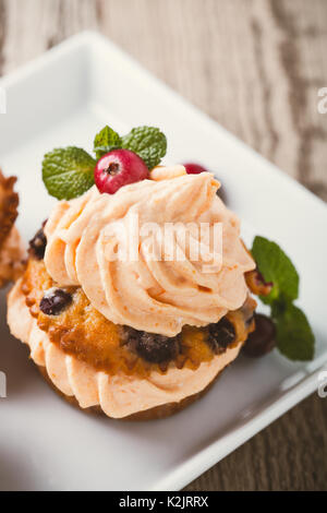 Cranberry pumpkin Cupcakes mit Cream Cheese frosting auf rustikalen Urlaub Tabelle Stockfoto