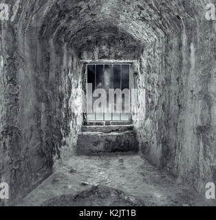 Stein Dungeon mit Fenster und Bars. Dunkle Töne. Stockfoto